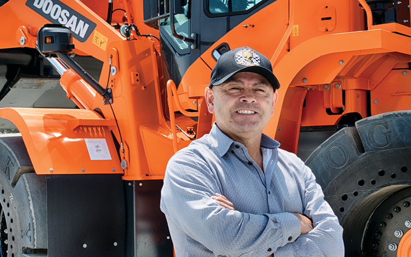 Mike Salinas, owner of Valley Services and Scrappers Racing, stands in front of his Doosan wheel loader.