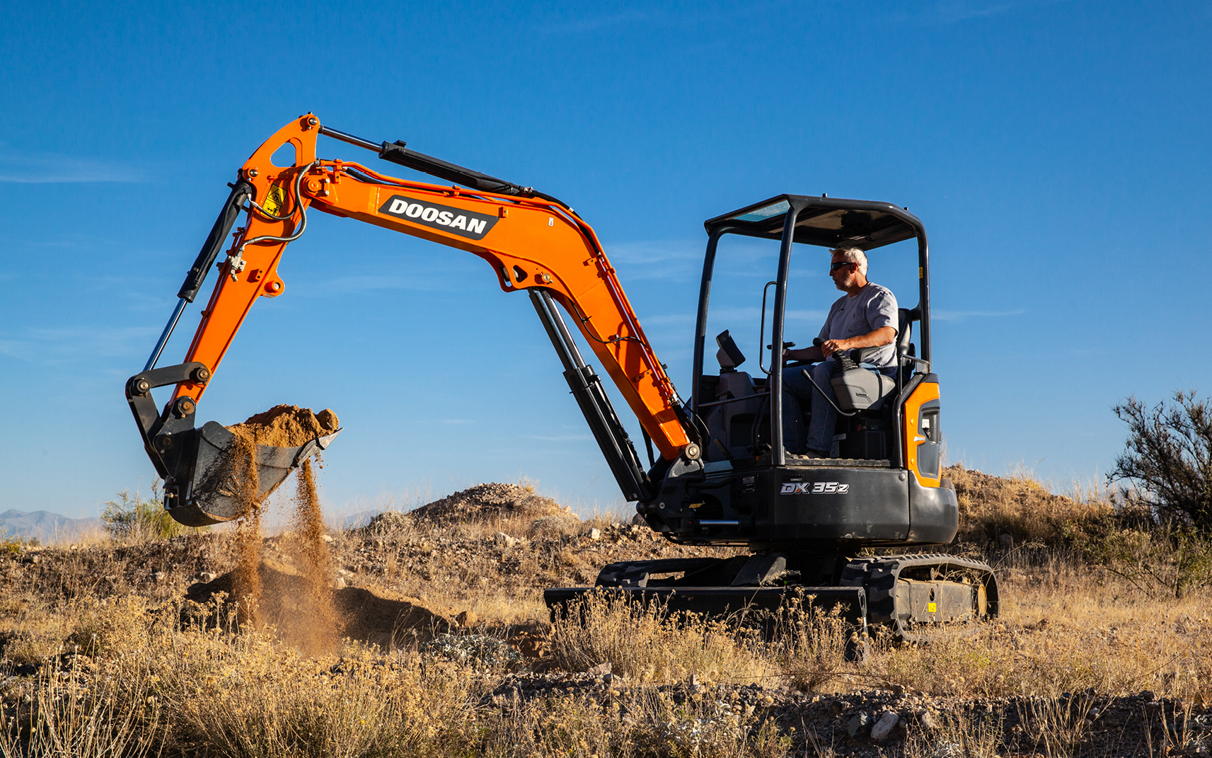 A DX35Z-7 mini excavator lifts a bucket of dirt.