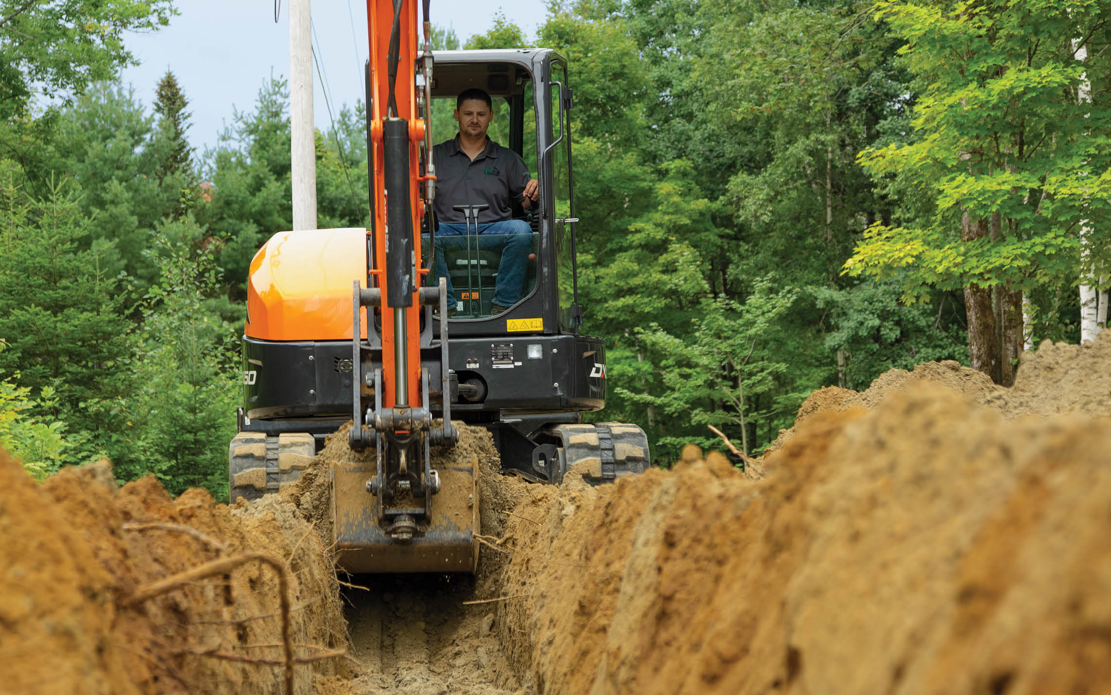 A Photo of Mike Hassett, Owner of Green State Excavating, Digging a Trench With His Doosan DX50-5 Mini Excavator.