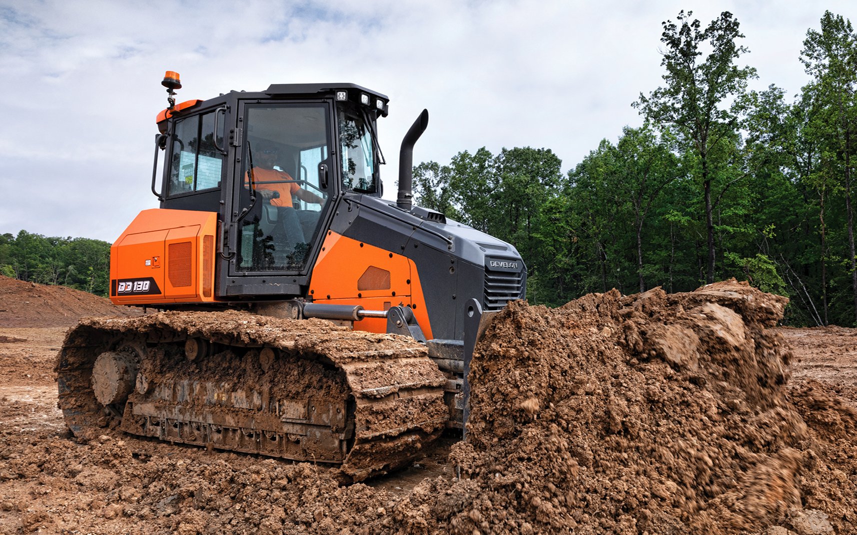 A DEVELON DD130 dozer pushes mud and dirt on a jobsite.