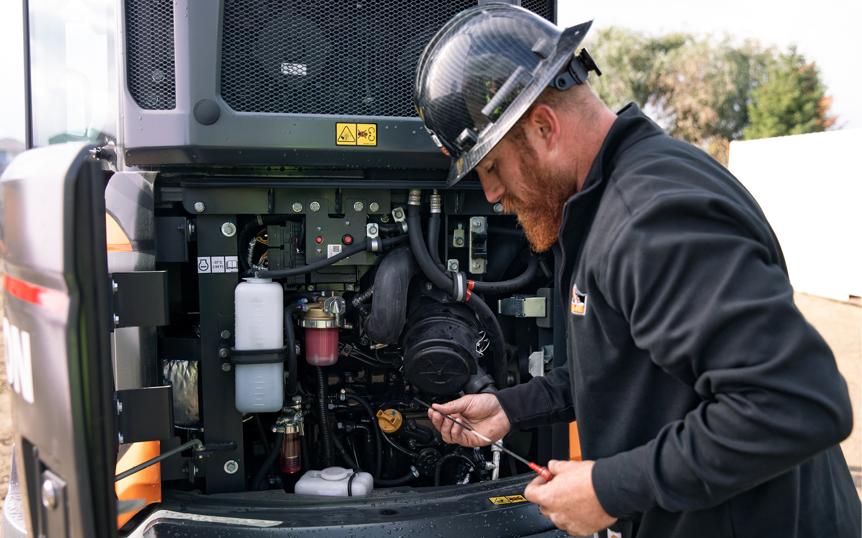 An operator checks the engine oil of a mini excavator.
